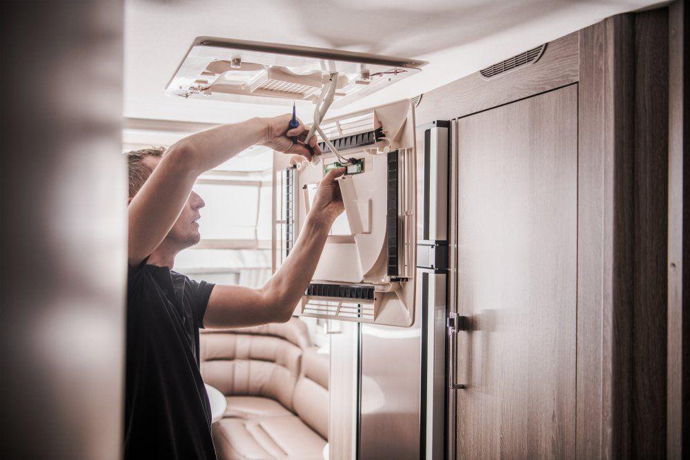 Technician repairing a rooftop RV air conditioner